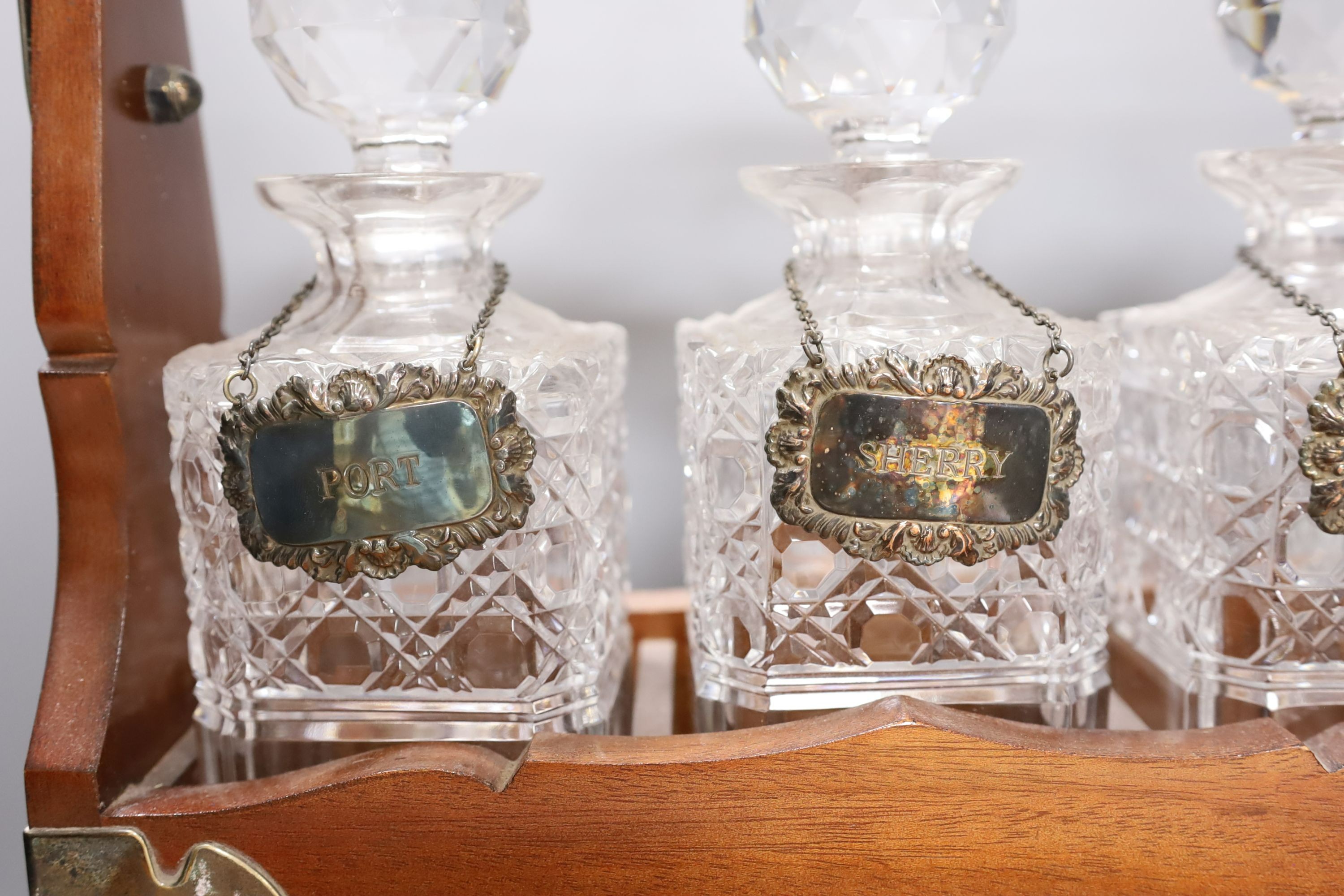 A three decanter tantalus - with labels, together with an oak canteen of table plated cutlery